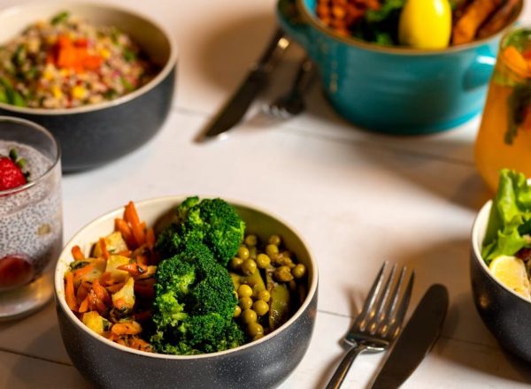 Delicious colorful bowls of salad and fresh beverages on a white table, perfect for healthy dining.