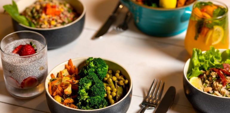 Delicious colorful bowls of salad and fresh beverages on a white table, perfect for healthy dining.