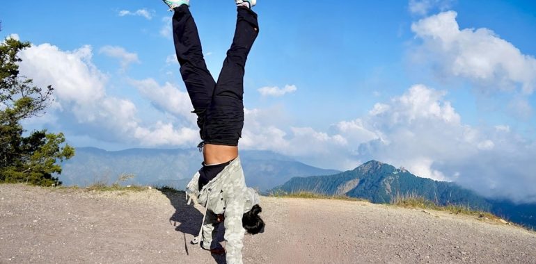 Person doing a handstand on a mountain path
