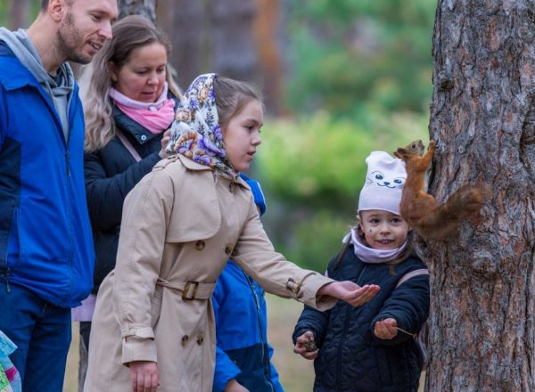 Family feeding a squirrel in a forest